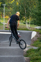 Fototapeta premium Young man doing tricks on a BMX bike. BMX freestyle against the backdrop of urban landscape. Extreme sports is very popular among youth. 