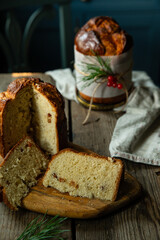 Two homemade Christmas panettone , one cut and the other whole, on wooden table on rustic kitchen with blue furniture.