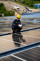 Male engineer checking solar cell  or photovoltaic cell by computer laptop installed on the roof of the factory. Technician worker repair or inspect the system. Industrial renewable energy concept