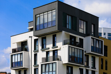 City view on a sunny day. Modern building and houses against the blue sky.