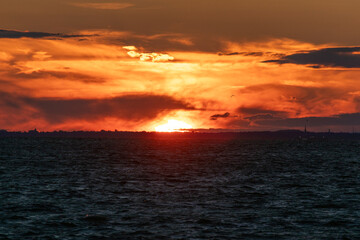 Fototapeta premium The sky is on fire in this photo of the sun setting over the bay in New Jersey. Image captured from Fort Hancock at Sandy Hook on August 21, 2024.