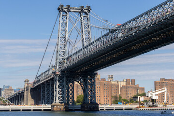 A clear day view of the Manhattan skyline and Williamsburg Bridge with modern skyscrapers under a blue sky