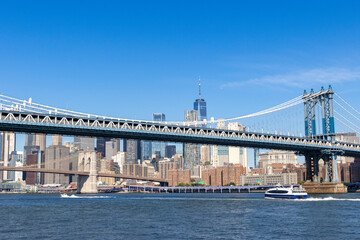 A clear day view of the Manhattan skyline and Williamsburg Bridge with modern skyscrapers under a blue sky
