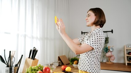 Obraz premium Happy mother chopping at vegetable or making salad and pose at camera. House keeper prepare fresh ingredients while looking at camera. Smart mom cooking at modern kitchen with kitchenware. Pedagogy.