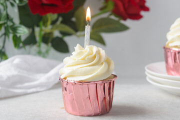Pink cupcakes with tall buttercream swirl and a lit candle, cupcakes in pink foil liners with vanilla buttercream and a candle