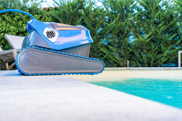 Automatic Pool Cleaner by the Poolside with Garden Background