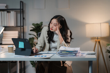 The Weight of Responsibility: A young businesswoman stares intently at her laptop, her face etched...