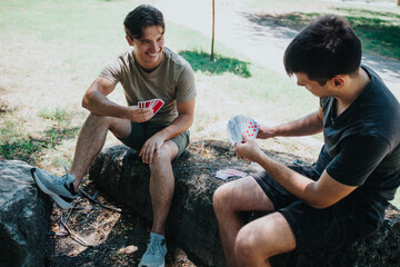 Two friends enjoying a card game outdoors on a sunny day
