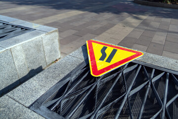 temporary road sign warning of a road narrowing lies abandoned on a ventilation duct, symbolizing...