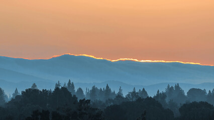 Sun painting Santa Cruz Mountains Ridgeline and above Hazy Forest, via Byxbee Park, Santa Clara...