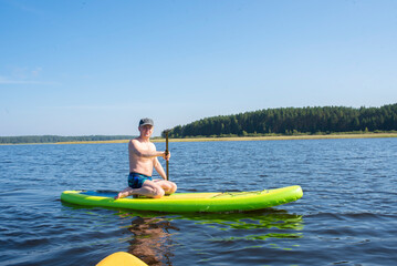 Man on stand up paddle board, spends holidays on  Seliger lake in summer.