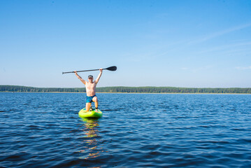Man on stand up paddle board, spends holidays on Lake Seliger in summer.