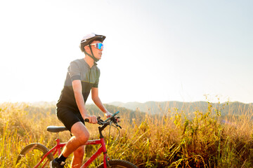 Cyclist riding a bike on a trail on a sunny day. He is wearing cycling gear and apparel. Inspirational image of a healthy lifestyle through cycling