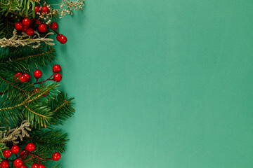 Christmas flat lay. Green fir branches, red berries on green background. Merry Christmas. Stylish christmas border with space for text. Xmas background