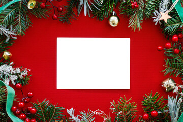 Christmas card mock up. Empty greeting card flat lay with fir branches, red berries and golden ornaments on red background. Merry Christmas. Season greetings template © sonyachny