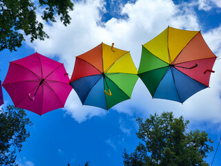Under the blue sky, under the colorful umbrellas hanging over the alley of the city park