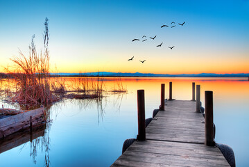 paisaje de un lago con un embarcadero y el atardecer 