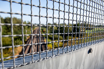 View of rails through metal grating, close-up of metal grating safety barrier