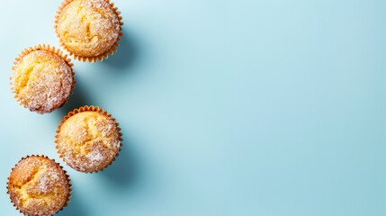 Three muffins are sitting on a blue background. The muffins are golden brown and have a slightly crispy texture. The muffins are arranged in a row, with one on the left, one in the middle