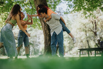 Young adults enjoying a sunny day in the park, having fun and playing together, expressing joy and...