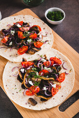 Tortilla with mushrooms, tomatoes, ricotta and onions on a board vertical view