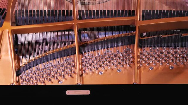 Close-up of the inside of a grand piano with strings, hammers and deck on a concert stage during a piano recital. Top view