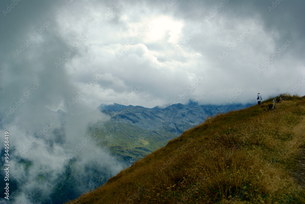 Wall mural mountain top with a wooden bench with a view of an amazing landscape on a hazy day with gray clouds 