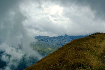 Mountain top with a wooden bench with a view of an amazing landscape on a hazy day with gray clouds and fog over the peaks in autumn in Austria.
