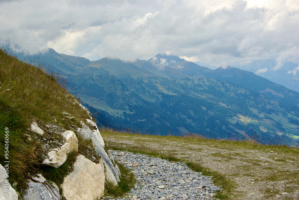 Wall mural view of an amazing mountain landscape with a stony path on a hazy day with gray clouds and fog over 