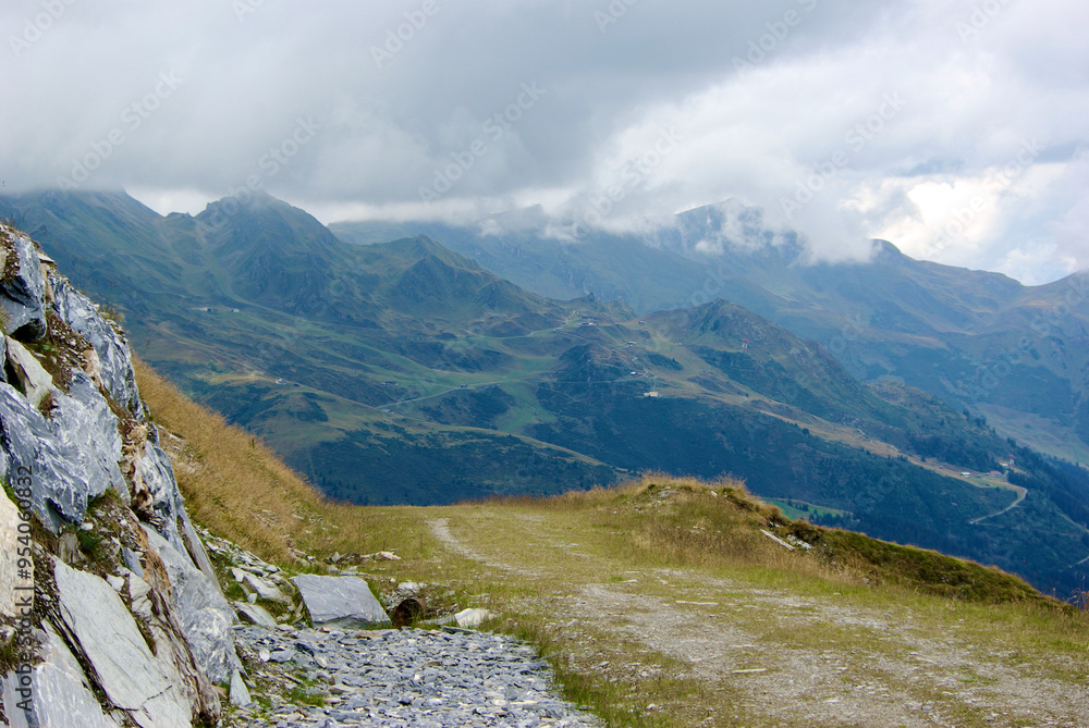 Wall mural view of an amazing mountain landscape with a stony path on a hazy day with gray clouds and fog over 