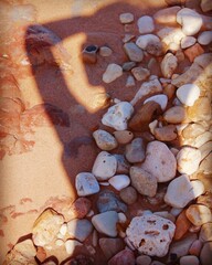 woman shadow on the sand with stones