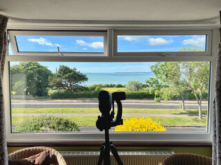 View of the sea through a large window in a room. There are two smaller windows one is open. There...