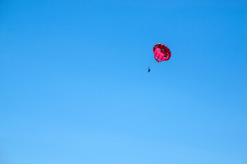 Two persons silhouettes doing parasailing on a blue sky