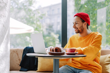 Happy freelancer working on laptop in cafe enjoying modern lifestyle