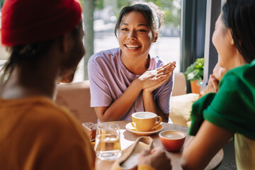 Young woman sharing exciting news with friends having coffee in cafe