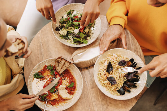 Top view group of friends sharing diverse lunch at restaurant table