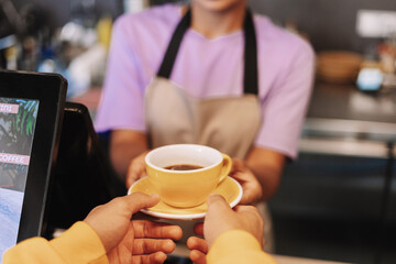 Barista giving customer cup of coffee in cafe selective focus service concept