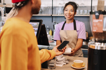 Customer making a contactless payment with smartphone in a coffee shop