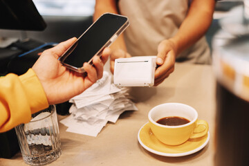 Customer using smartphone to make contactless payment for coffee