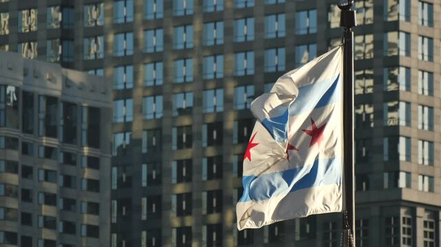 A vibrant shot of the iconic Chicago flag, with its four red stars and blue stripes, fluttering in the breeze against the backdrop of the city's towering skyscrapers. A symbol of pride and urban life