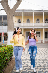 Two young women walking and listening music in the city