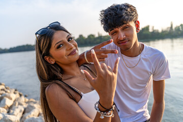 beautiful young couple of teenagers having fun making funny faces on the river bank