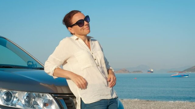 Female stand by car against sea. A happy woman driver stand by the car against sea landscape in summer.