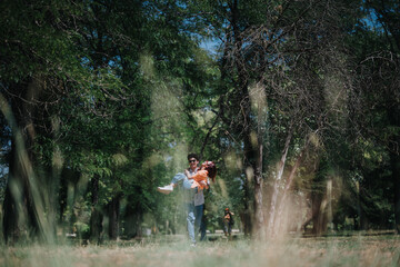 Fototapeta premium Young couple enjoying a playful moment in the park surrounded by lush trees and greenery, capturing love and joy.
