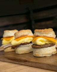 Breakfast biscuits with egg, sausage, and cheese on wood serving board