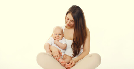 Happy smiling young mother playing with cute baby sitting together on the floor on white background