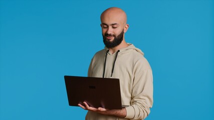 Young adult waving at videocall connection on laptop, attending briefing session on online videoconferencing call. Middle eastern guy talking to people on internet network meeting. Camera 1.