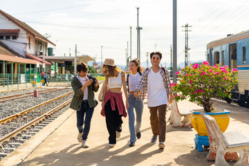 Group of Asian man and woman enjoy and fun outdoor lifestyle travel countryside by railroad transportation on summer holiday vacation. Generation z people friends walking together at train station.