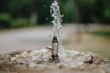 A detailed image of a water fountain valve spraying water, set against a blurred background...