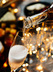 Pouring sparkling wine or champagne served on the table for Christmas or New Year eve celebration. © FornStudio